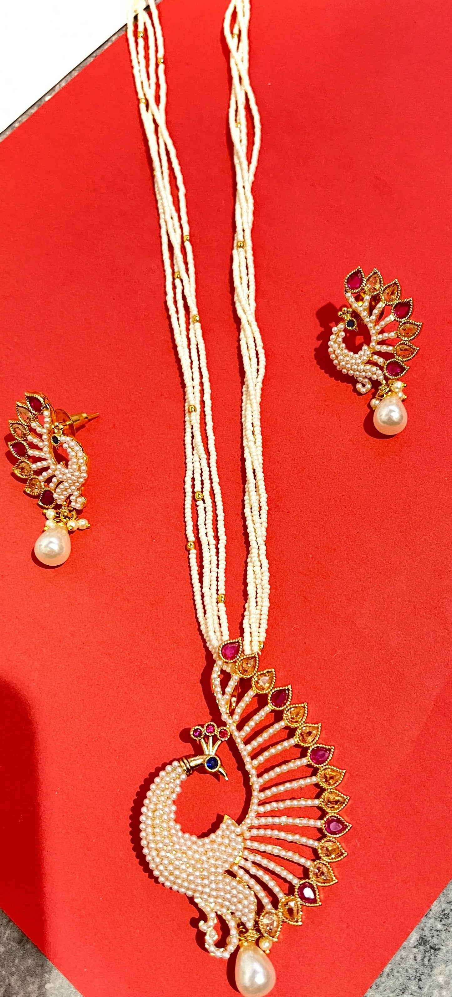 A multicolor peacock pendant with earings and a mala